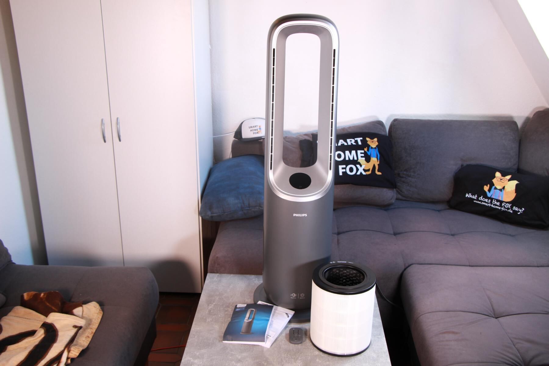 Der Lieferumfang des Philips Air Performer 8000 liegt neben dem Gerät auf einem Couchtisch übersichtlich dargestellt.